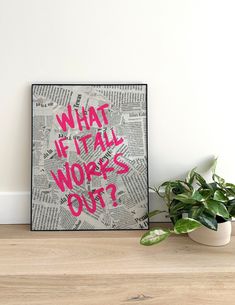 a poster with the words what if it all works out? in pink on top of a wooden table next to a potted plant