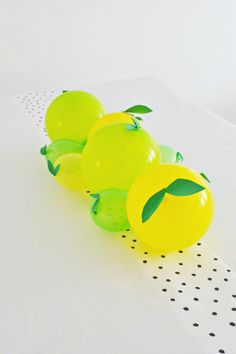 three balloons with green leaves on them are lined up against a white tablecloth that is dotted with black dots