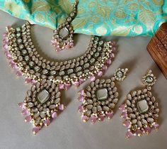 Be the beautiful bride in our designer pink kundan bridal jewelry set with a hint of green meenakari! The pink beads add a touch of softness to it's appeal.  Unfold the euphoria of this majestic bridal jewelry set in an enticing style that is sure to elevate your look. Details: Choker Necklace Width-2 Inches Pendant hanging at Necklace Centre-3 Inches Earrings Length-4.5 Inches Earrings Width-2 Inches Weight of Each Earring-32 gms Tika Length-4.5 Inches All products are manufactured using traditional skills from our rich heritage of crafts.  The process of these crafts is essentially manual. Hence, any irregularities or variations are an inherent part of these handcrafting processes. Pink Kundan Necklace For Reception In Temple Jewelry Style, Pink Kundan Necklace Hand Set For Reception, Pink Kundan Necklace With Meenakari For Reception, Pink Kundan Chandbali Bridal Set, Pink Kundan Bridal Sets For Festivals, Pink Hand Set Kundan Temple Necklace, Pink Kundan Jewelry Sets With Stone Work, Pink Kundan Jewelry Sets For Reception, Pink Kundan Wedding Necklace With Stone Work