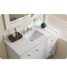 a white bathroom vanity with two sinks and a mirror above it, in front of a window