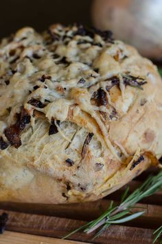 a loaf of bread sitting on top of a wooden cutting board next to some herbs