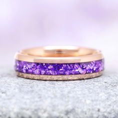 a purple and gold wedding band on top of a rock