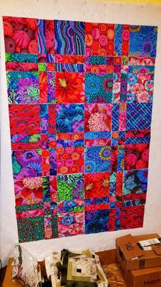 a colorful quilt hanging on the wall next to boxes