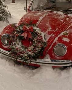 an old red car covered in snow with a wreath on the front