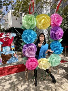 a woman standing in front of a giant paper flower wreath on top of a sidewalk