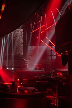 red and white lights shine brightly in the dark room with round tables on either side