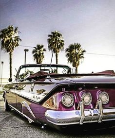 an old car parked on the side of the road with palm trees in the background