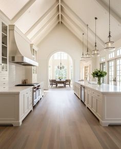 a large open kitchen with white cabinets and wood flooring is pictured in this image