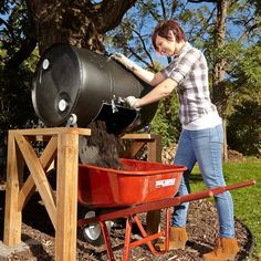 a woman is pushing a barrel into a wheelbarrow