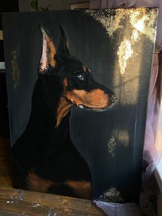 a painting of a black and tan doberman dog on a wooden table next to a window