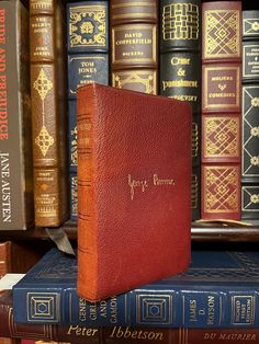 a red leather book sitting on top of bookshelves