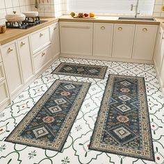 two rugs in the middle of a kitchen floor with white cabinets and counter tops