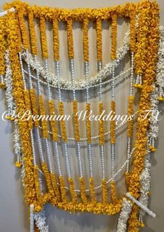 a wall hanging made out of yellow and white yarn with beaded trims on it