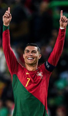 a soccer player is holding his hands up in the air and smiling at the camera