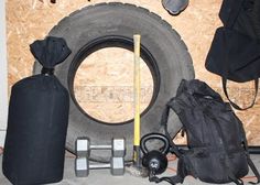 an assortment of sports equipment sitting on the floor next to a pile of plywood