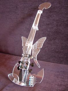 a glass guitar sculpture sitting on top of a purple couch