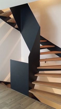 a wooden staircase with black railing and white walls