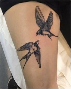 two birds are flying next to each other on the side of a woman's thigh