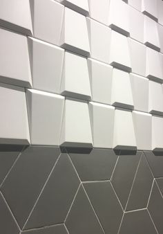 the wall is made up of white and gray tiles