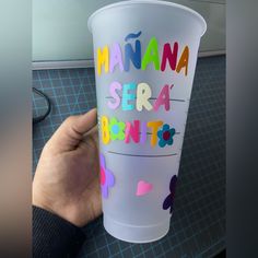 a person holding up a plastic cup with the words manana sera bento on it