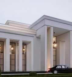 a black car is parked in front of a large white building with columns and windows