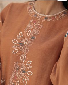 a close up of a person wearing a brown shirt with white flowers on the front