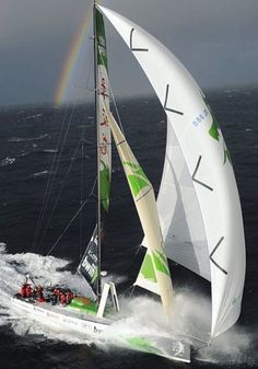 a sailboat with white and green sails is in the ocean under a cloudy sky