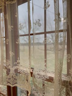 an open window with white lace curtains in front of it