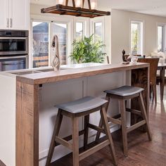 a kitchen island with stools in front of it and an open window to the outside