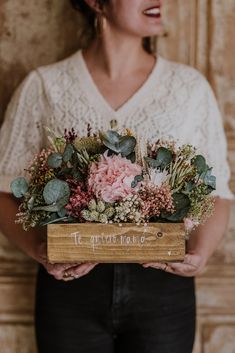 a woman holding a wooden box filled with flowers