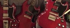 three red electric guitars are lined up in a row and one is on the floor