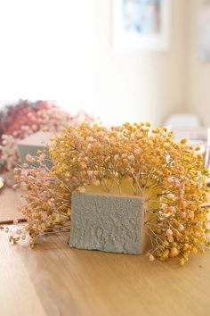 some yellow flowers on a wooden table and a vase with small plants in the middle