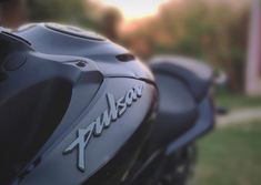 the front end of a black motorcycle parked in a driveway next to a grassy area