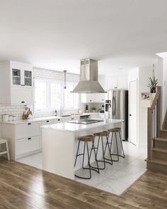 a kitchen with white cabinets and counter tops next to a staircase leading up to the second floor