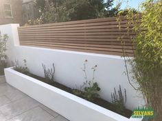 an outdoor garden with white walls and wooden slats on the fenced in area