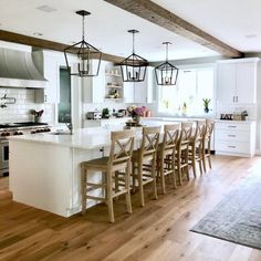 a kitchen filled with lots of white counter tops and wooden chairs next to an island