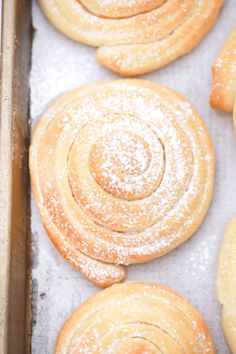 freshly baked pastries on a baking sheet covered in powdered sugar