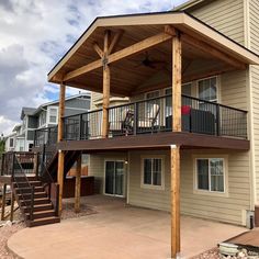 a two story house with a covered patio and stairs leading to the upper level deck