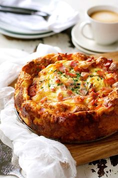 a pizza sitting on top of a wooden cutting board next to a cup of coffee