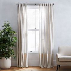 a living room with a chair, window and potted plant in front of it