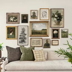 a living room filled with lots of framed pictures on the wall above a white couch