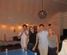 a group of people standing next to each other near a ping pong table in a room