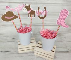 two cups filled with pink cake next to cowboy themed straws and paper cutouts