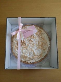 a cake in a box with a pink ribbon