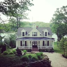 a large white house sitting next to a lush green forest