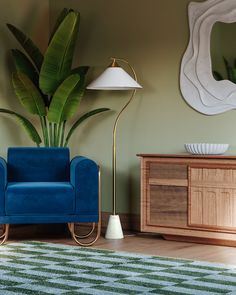 a blue chair sitting in front of a green plant next to a wooden dresser and lamp