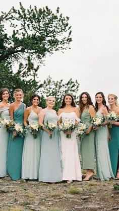 a group of women standing next to each other on top of a hill holding bouquets