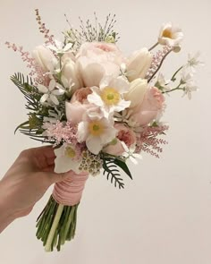 a person holding a bouquet of flowers in their hand with the other hand on it