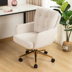 a white office chair sitting on top of a hard wood floor next to a plant