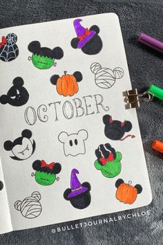 an open notebook with mickey mouses and other halloween stickers on it next to markers